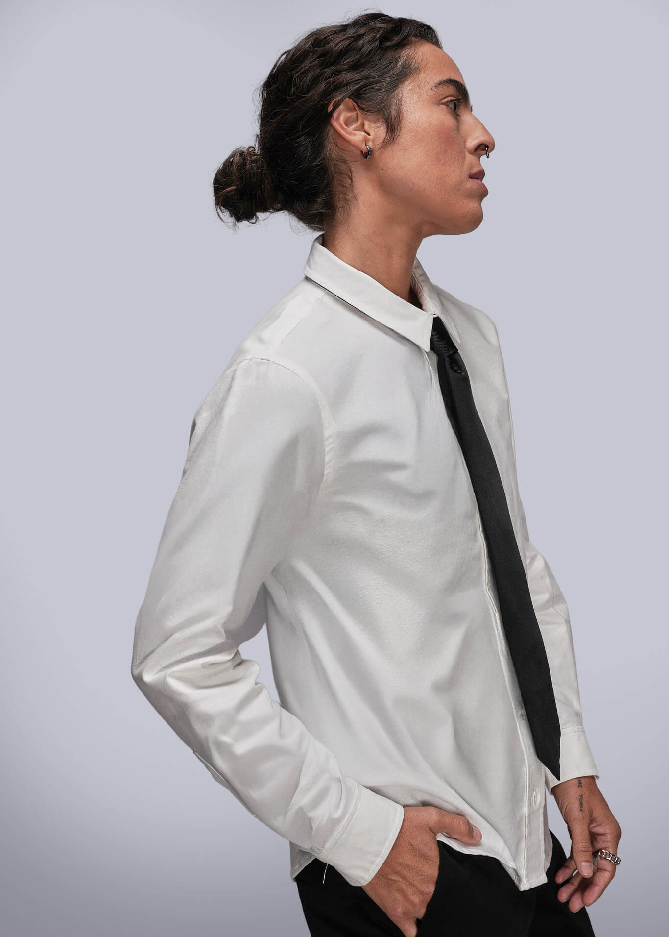 S=Person wearing a white shirt with a black tie against a plain background