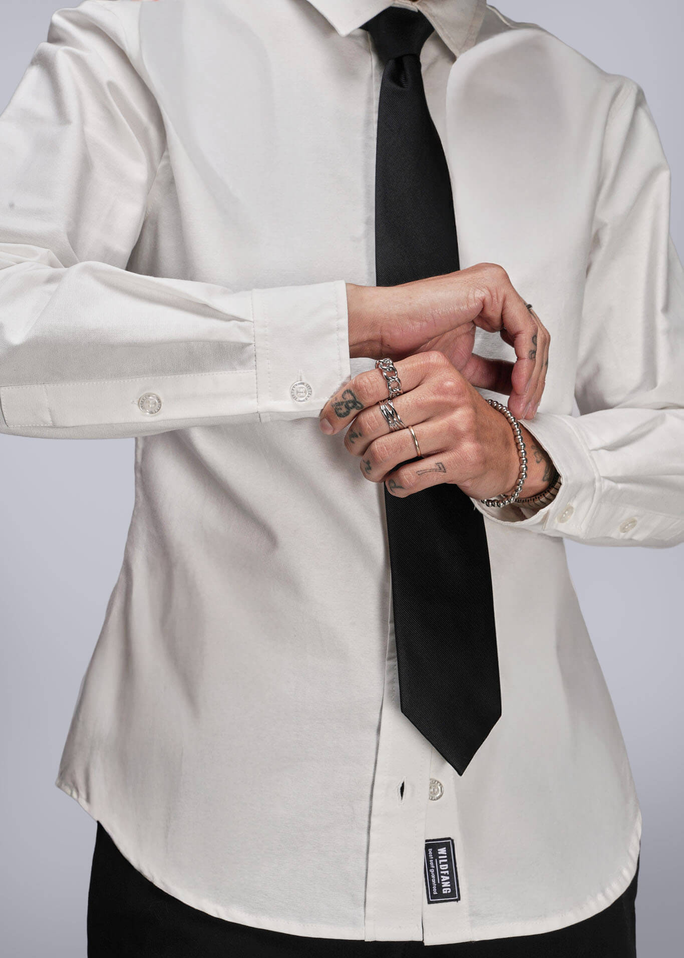 S=Person wearing a white dress shirt with a black tie against a plain background
