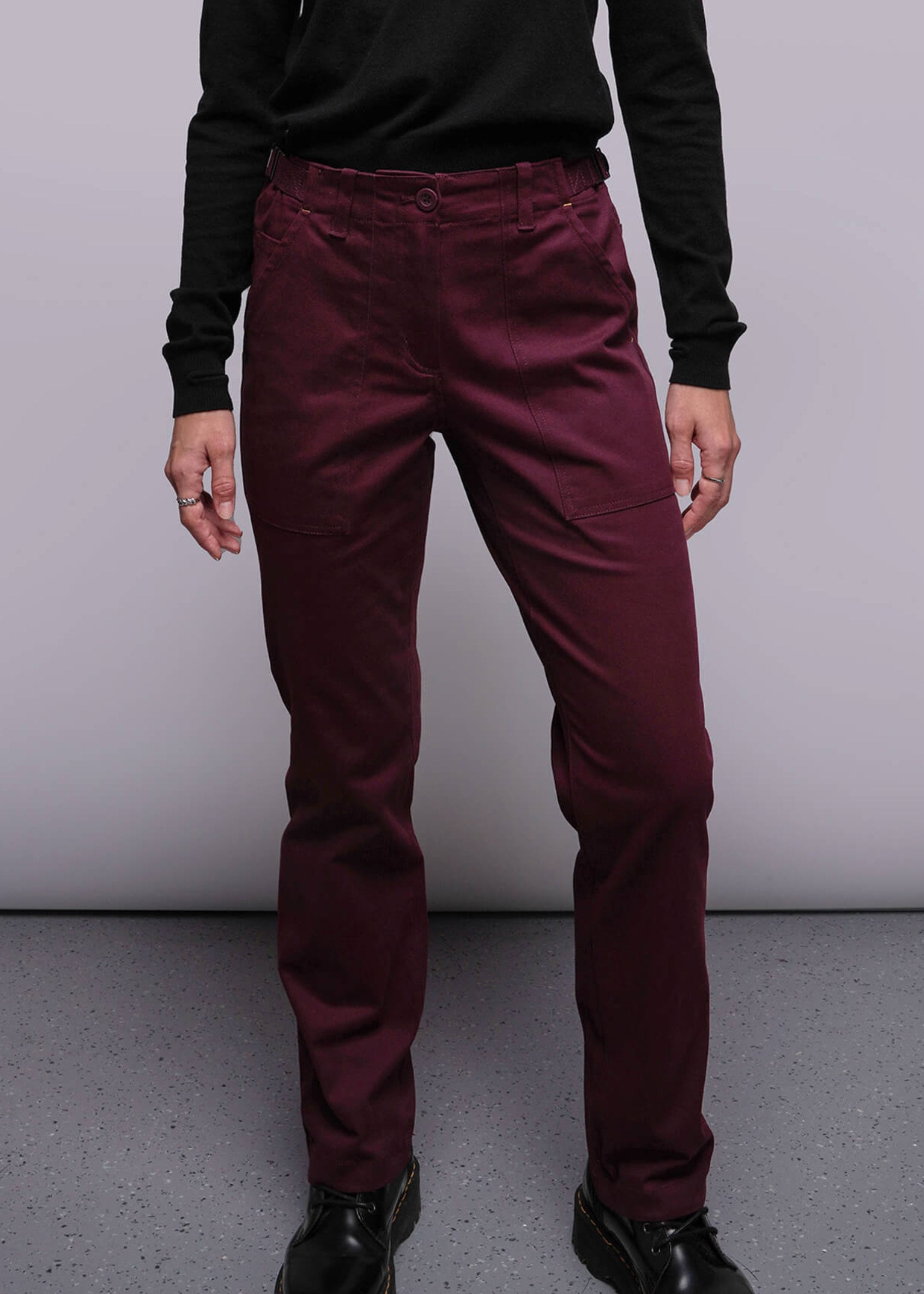 S=Person wearing maroon pants and black shoes on a plain background