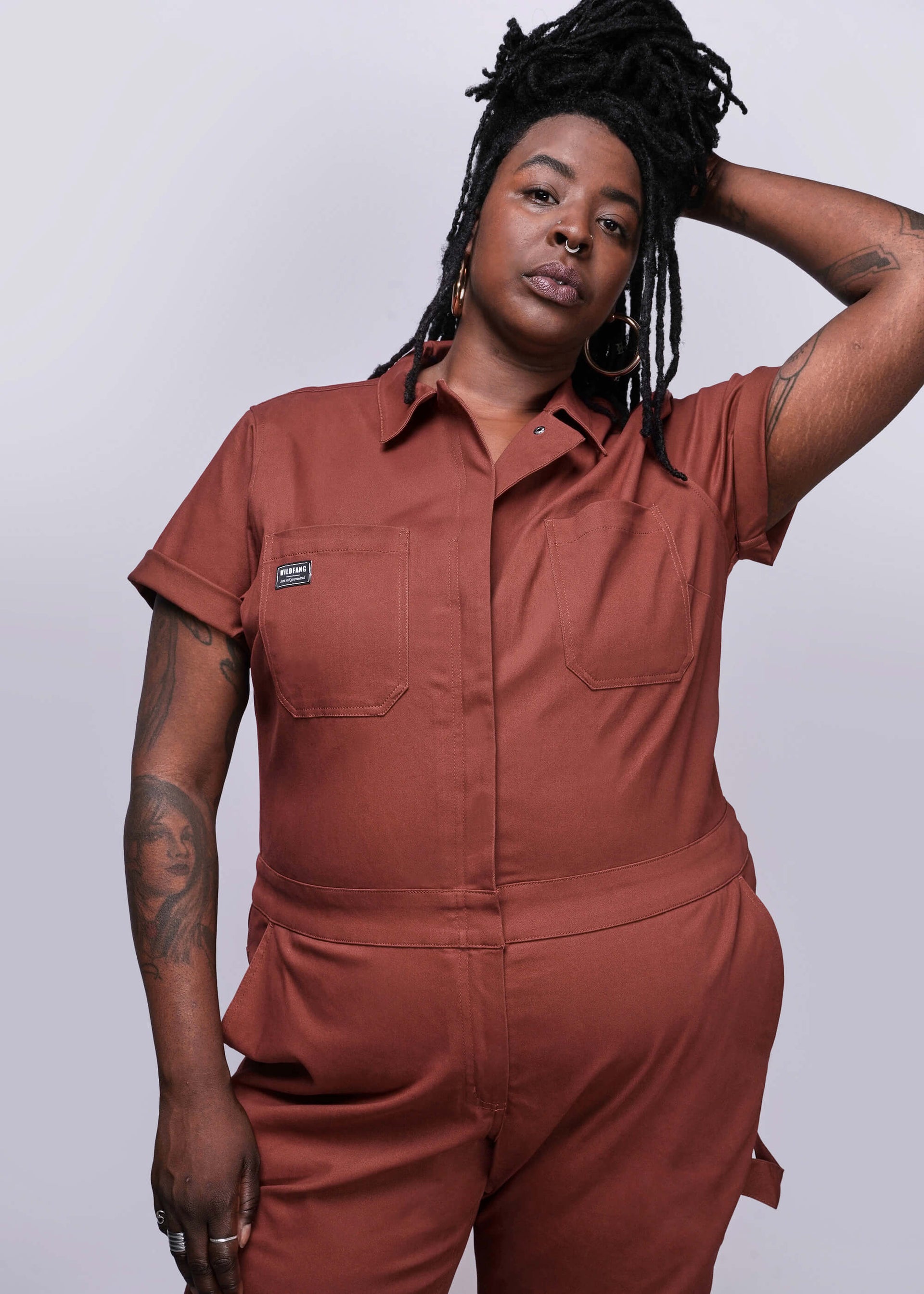 1X=Person wearing a brown jumpsuit against a plain background