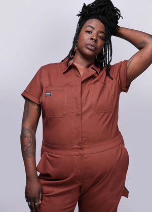 1X=Person wearing a brown jumpsuit against a plain background