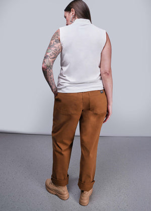S=Person wearing a white sleeveless shirt and brown pants against a gray background