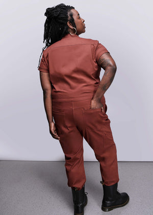 1X=Person wearing an orange brown jumpsuit against a white background