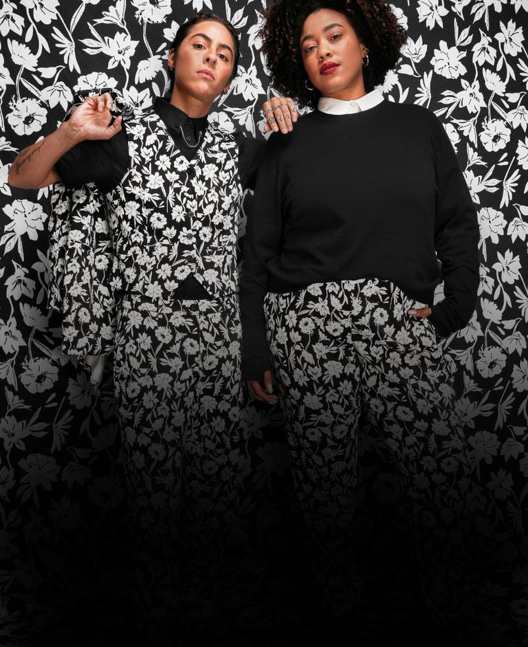 In front of a black and white patterend balckground, two models wear suiting pieces from the black friday exclusive collection.