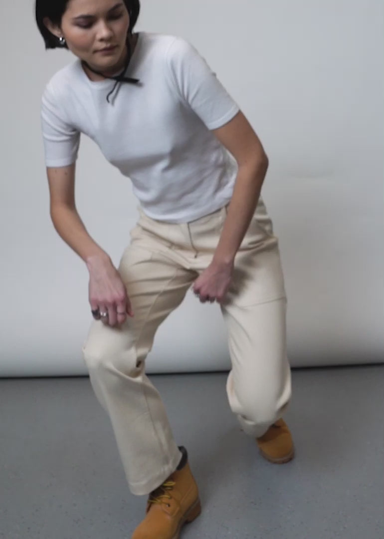 Video shows models of two different sizes wearing The Essential Utility Pant. Video features close ups of the front and back pockets, adjustable waist detail, and shows models bending and crouching to show stretch in fabric.