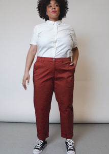 Video shows model wearing The Essential Trouser in Cinnamon. Shows close ups of from and back pockets and bottom cuff. Model kicks leg and spins to show comfortable fabric with stretch.