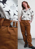 Video shows two models of different sizes wearing The Essential Utility Pant in Walnut. Close up shots show back and side pockets, the adjustable waist, and how the pant moves when the model squats. The video ends with a split screen side by side of the two models to show how it fits in different sizes.