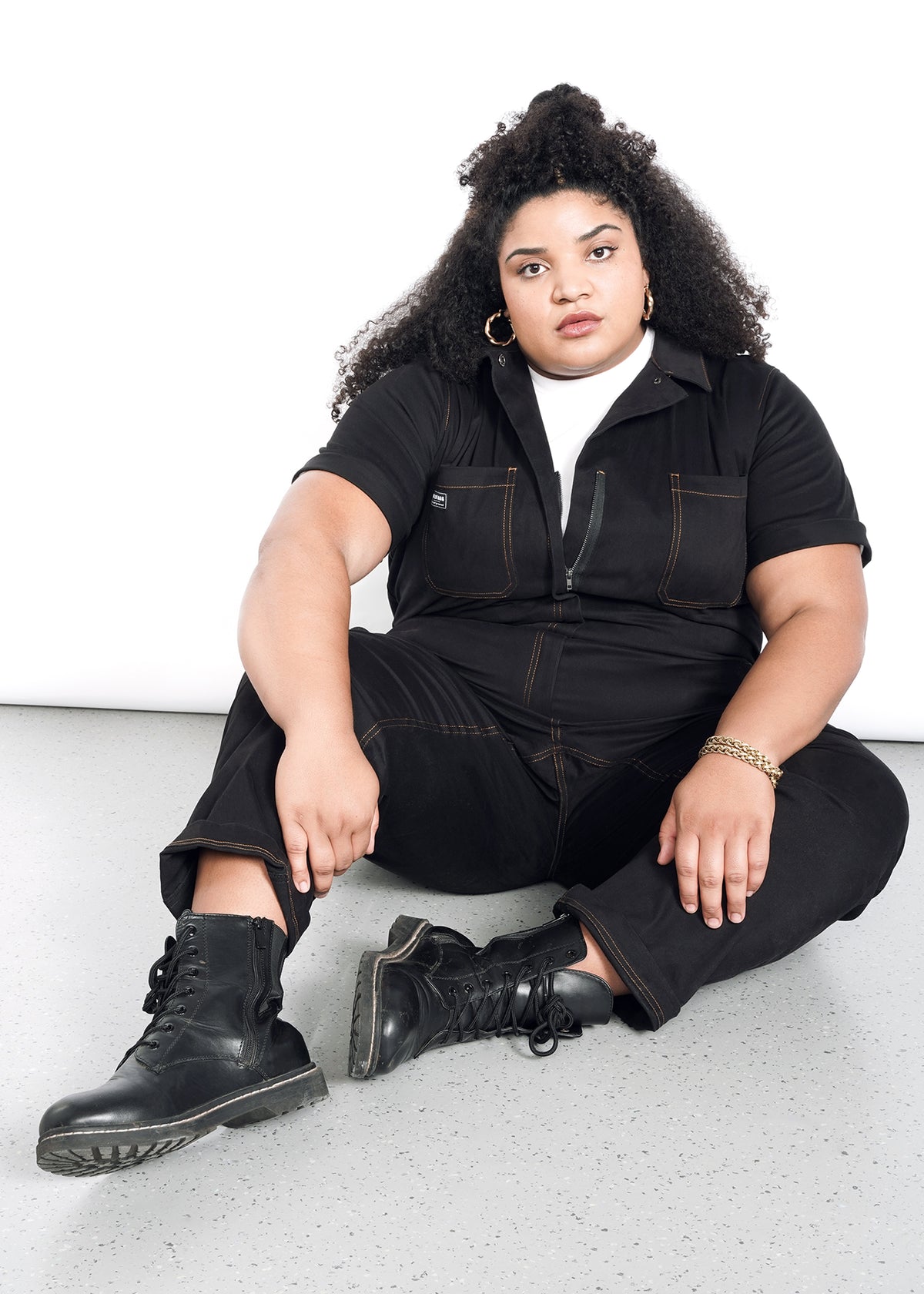 model wearing black cotton stretch coverall jumpsuit boiler suit short sleeve with brown spice colored pop stitching