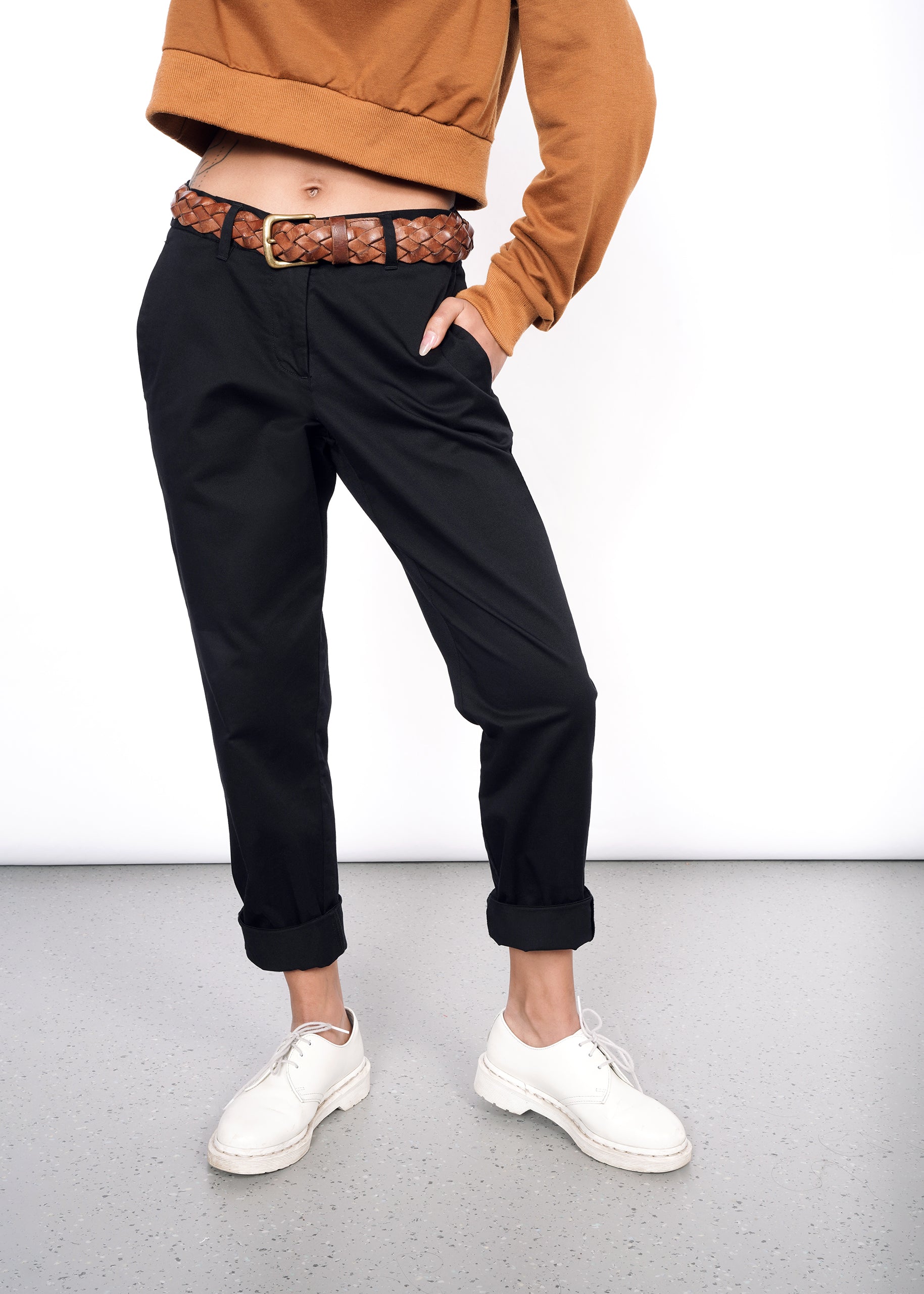 Model wearing black essential trouser pant in size 2, with hand in pocket and pant legs cuffed up