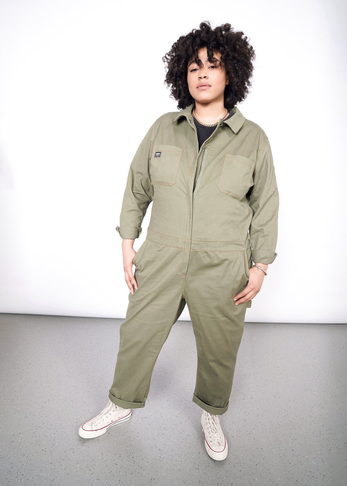 Tambrie is wearing the olive long sleeved coveralls in size XXL, with a gray tee and white converse
