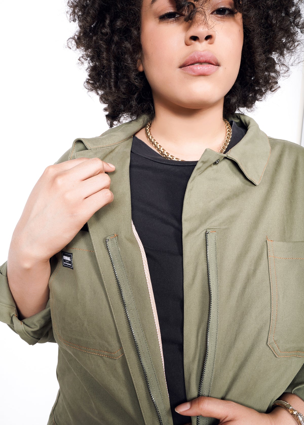 Model wearing coveralls with zipper unzipped, showing interior lining, top button, and details