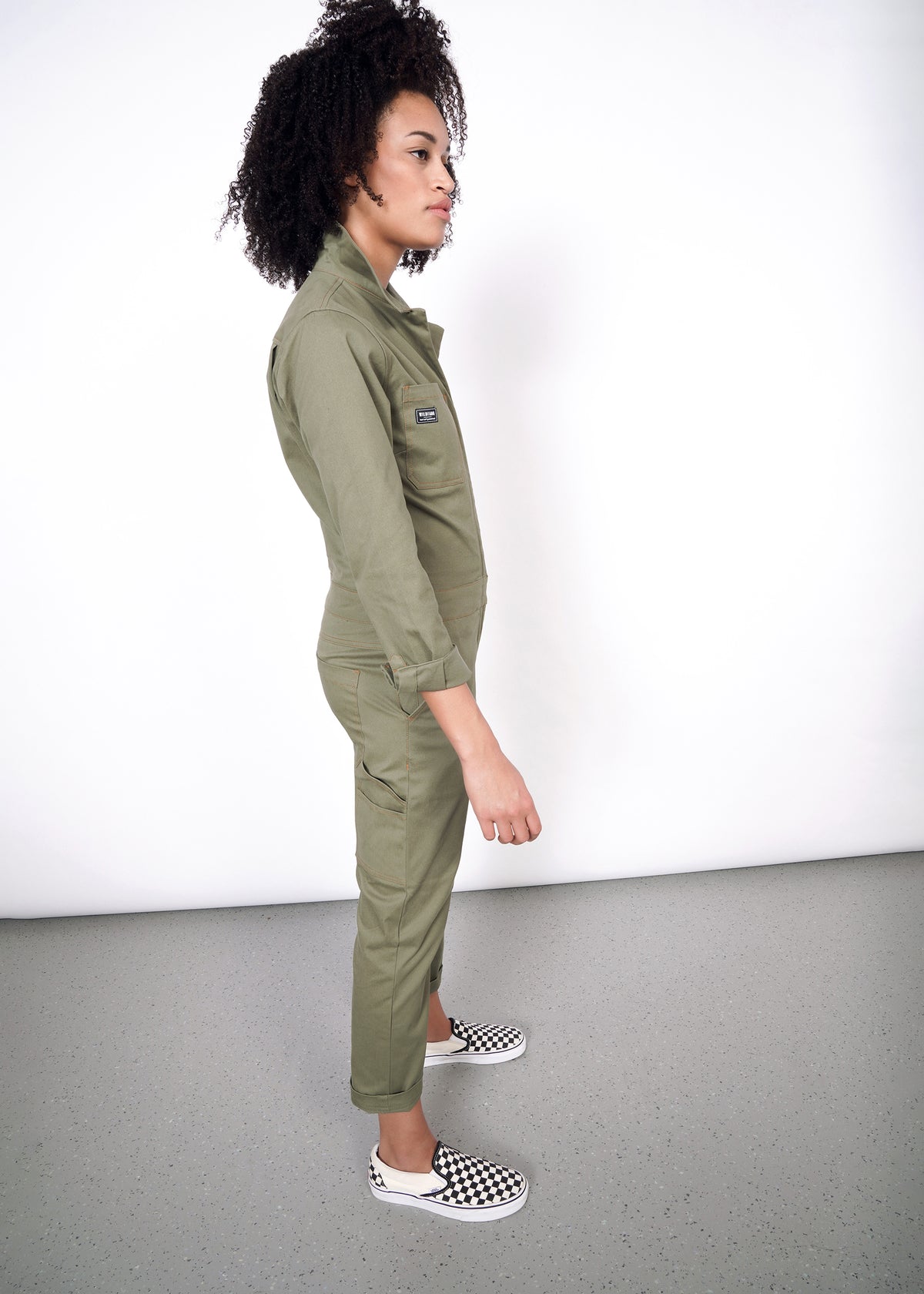 Model wearing olive coverall in size small, showing side body view